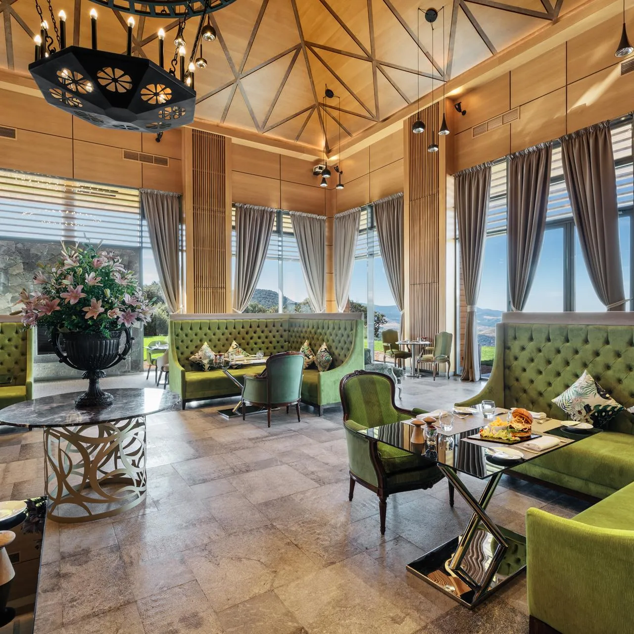 An elegant restaurant with green banquettes, set tables, and large windows offering a panoramic view.