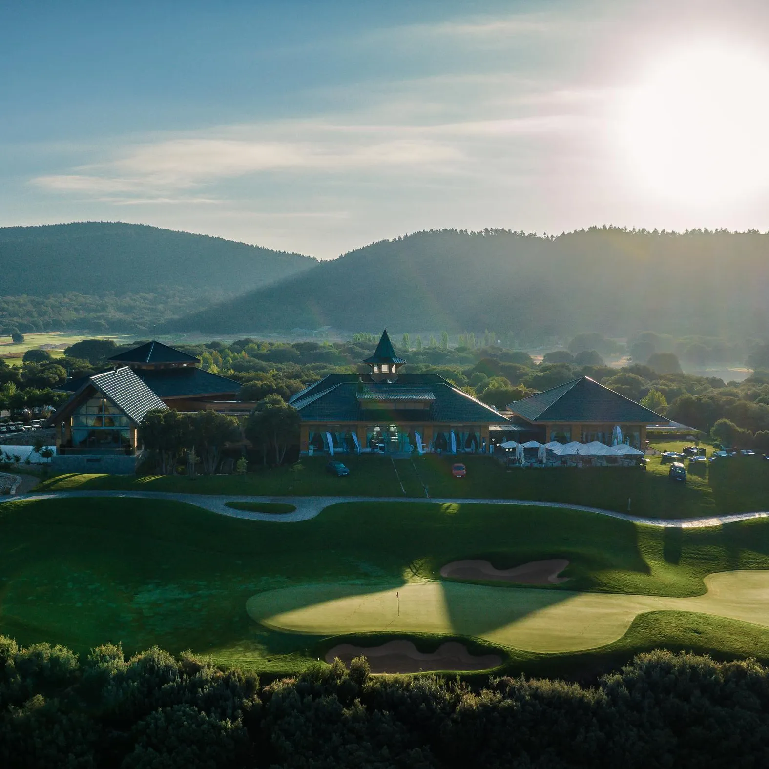 A golf course with buildings and mountains in the background under a clear sky