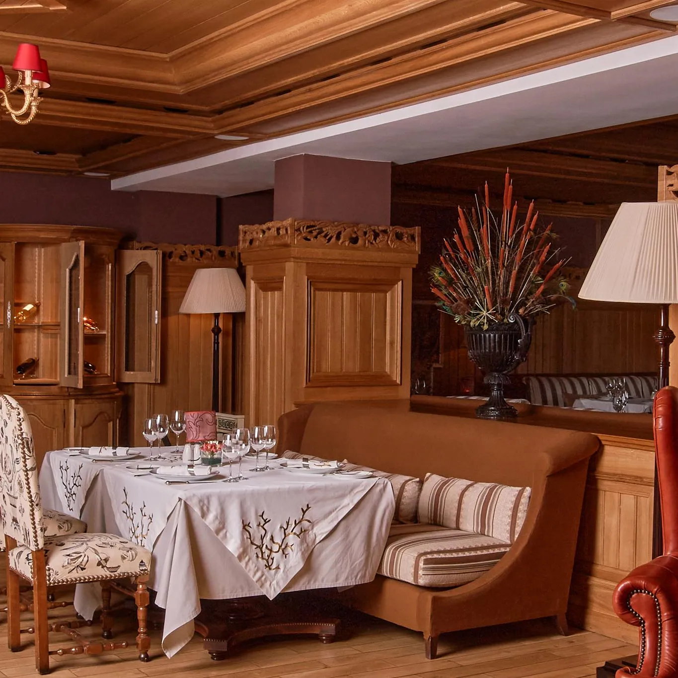 Elegant dining room with set table, chandelier, lamps and leather sofas