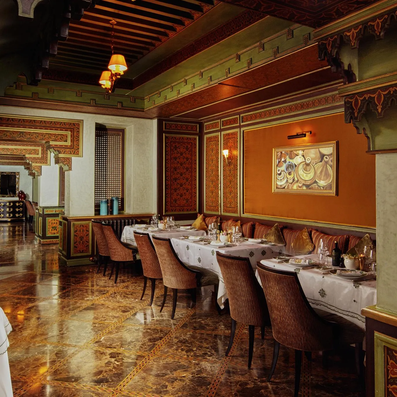 Elegant restaurant with set tables, padded chairs, and walls decorated with traditional patterns