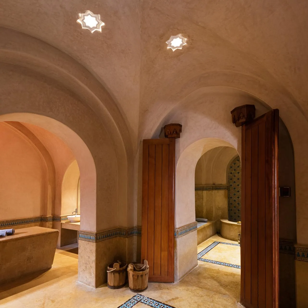 Hall with arches and vaults featuring decorative tiles on the floor and walls, as well as basins.