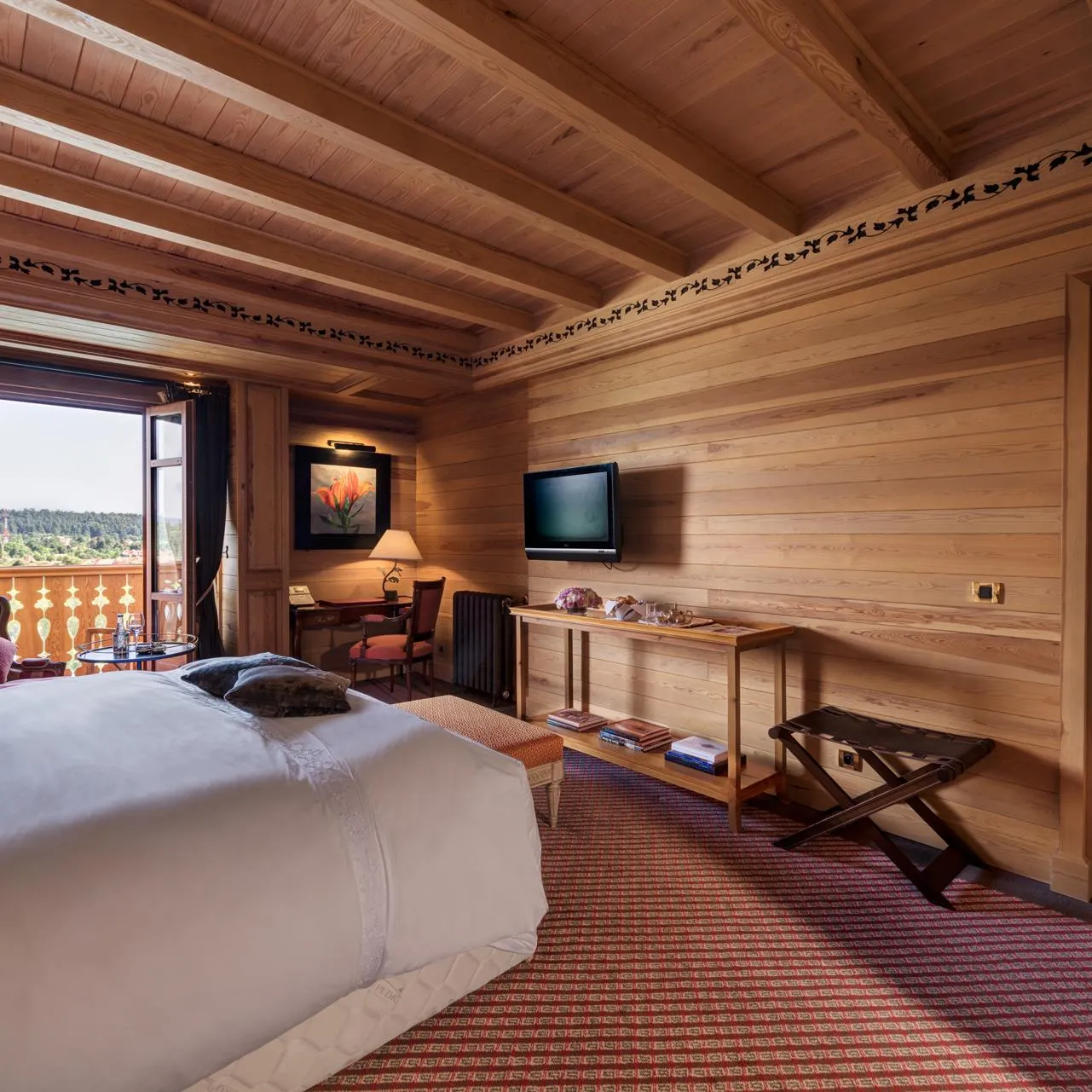 Wooden room with two beds, a television, a desk, and an outdoor view through a sliding door.