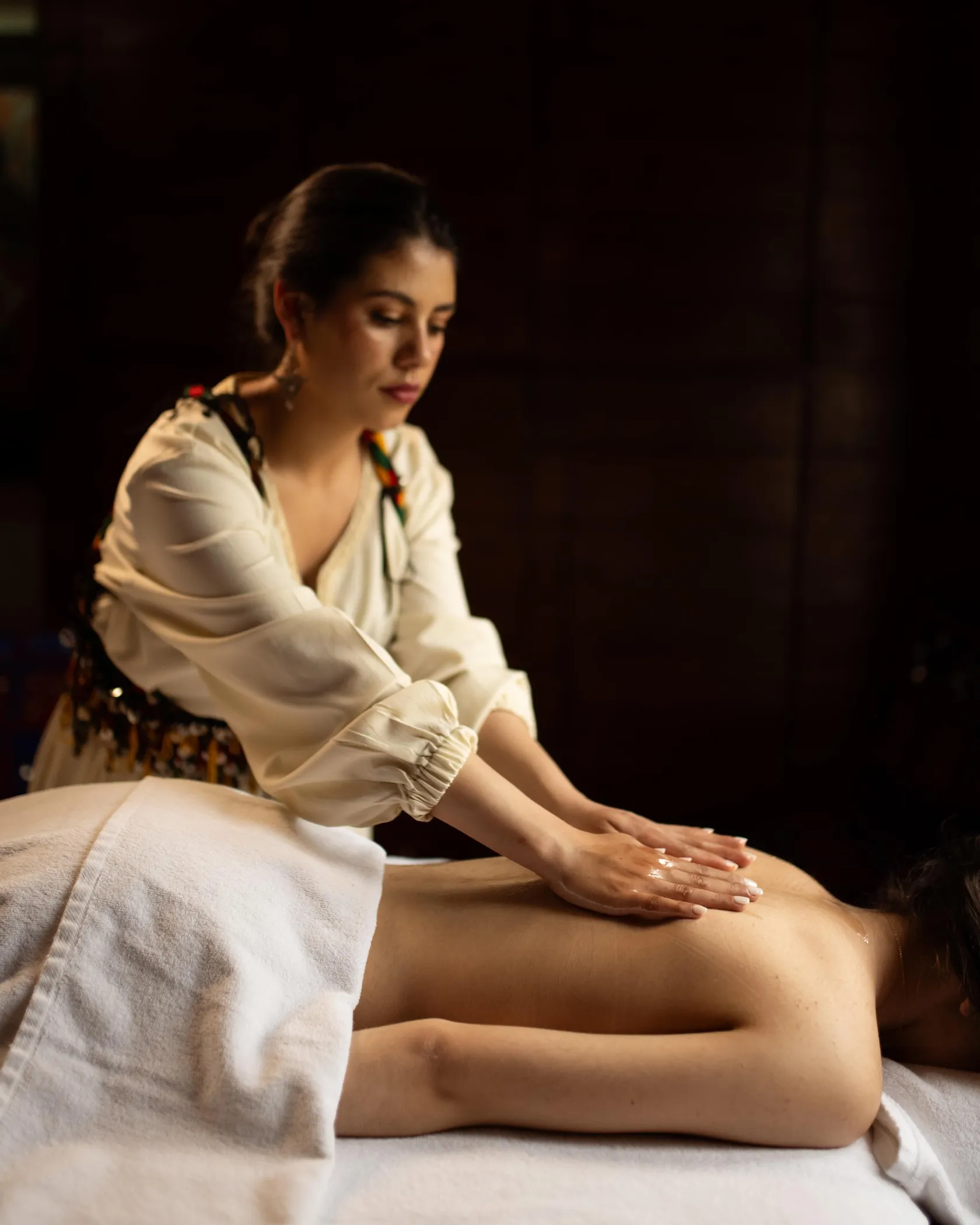 A person performs a massage on the back of another person lying face down.