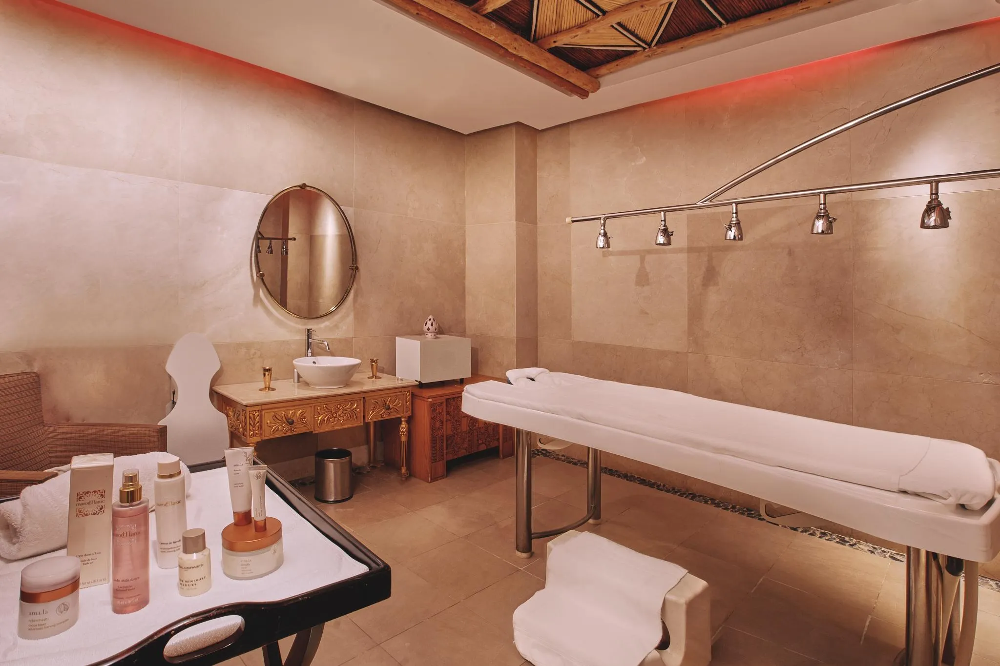 Treatment room with massage table, mirror, sink, and cosmetic products on a table
