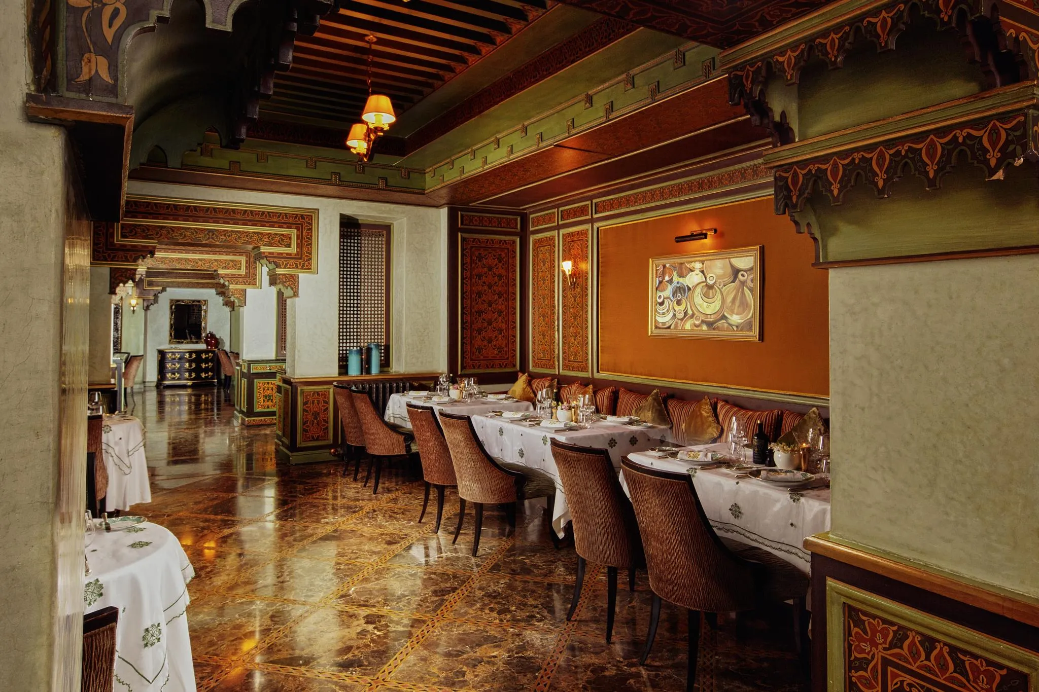Elegant restaurant with set tables, padded chairs, and walls decorated with traditional patterns
