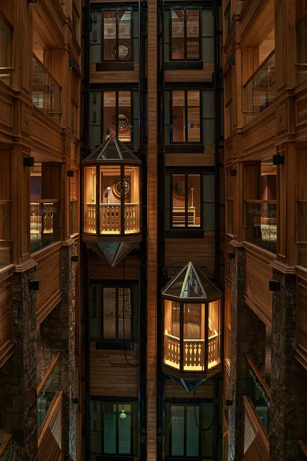 Vertical view of an indoor atrium with illuminated wooden balconies and glass windows