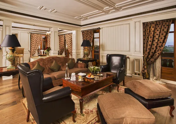 Elegant lounge with brown leather sofa, black leather armchairs, wooden coffee table, and floral decorations