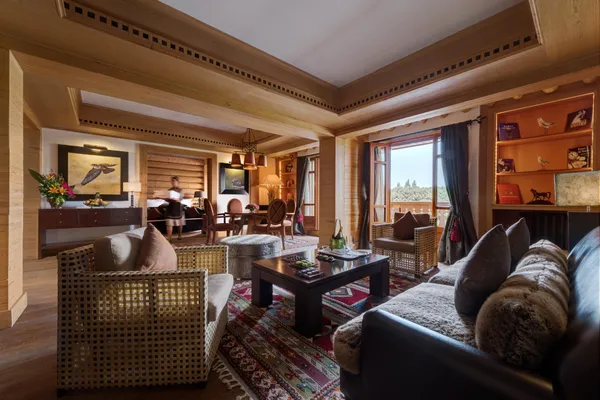 Wooden lounge with sofas, armchairs, coffee table and outdoor view through large windows