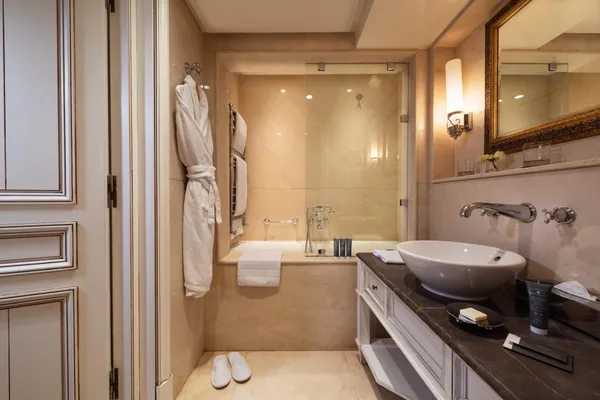 Bathroom with bathtub, sink, mirror, towels, and hanging robes